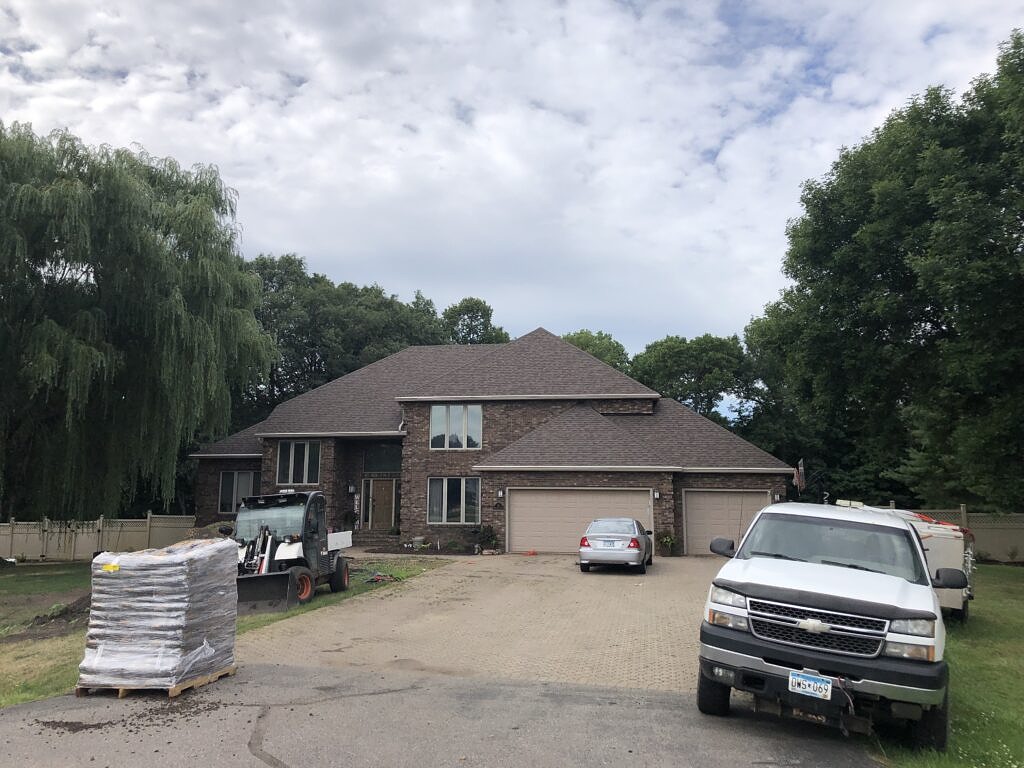 House with dark brick siding and a teak colored roof.