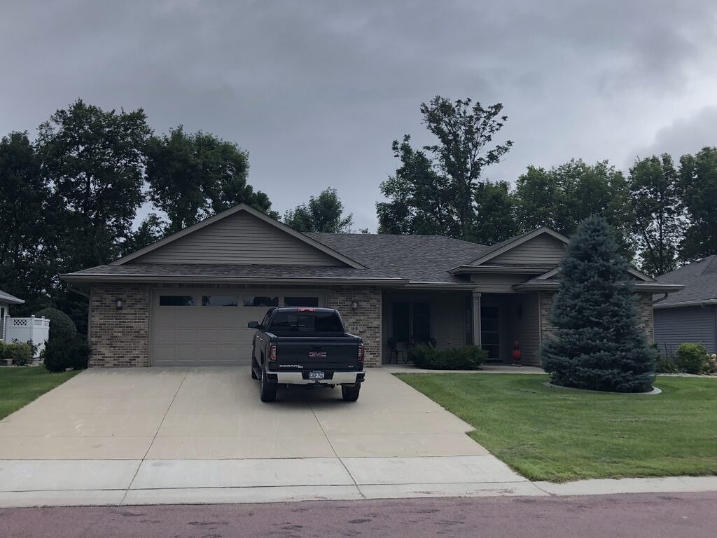 House with brick siding and a driftwood colored roof.